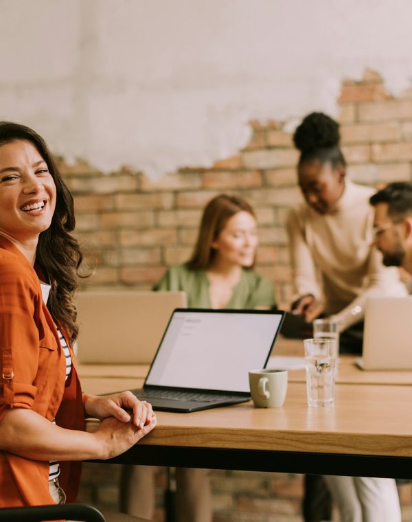 Business woman working on laptop with her young multiethnic startup team in the modern office